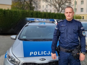 policjant stoi przy radiowozie policyjnym