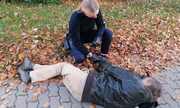 Policjantka pomaga mężczyźnie leżącemu na ziemi