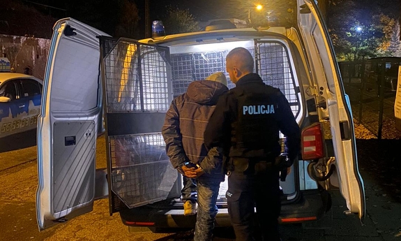 policjant trzyma zatrzymanego przy radiowozie