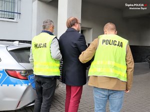 policjanci prowadza zatrzymana osobę