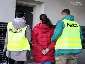 policjanci prowadza zatrzymana osobę