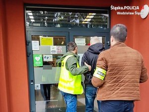 policjanci prowadza zatrzymana osobę