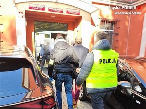 policjanci prowadza zatrzymana osobę