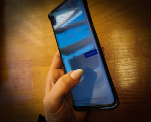 Kobieca dłoń trzyma telefon, na którym jest włączona aplikacja do logowania