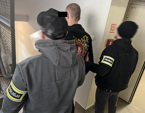 dwaj policjanci z zatrzymanym mężczyzną zakutym w kajdanki