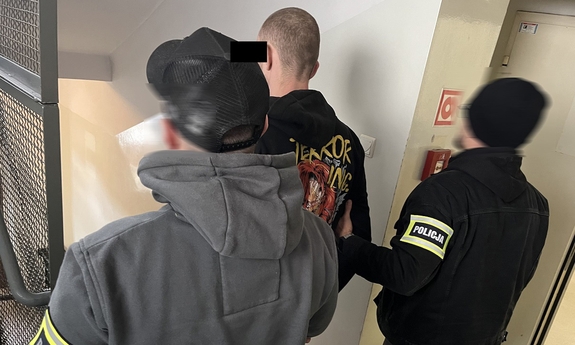 dwaj policjanci z zatrzymanym mężczyzną zakutym w kajdanki