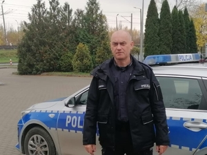 policjant stoi przy radiowozie policyjnym