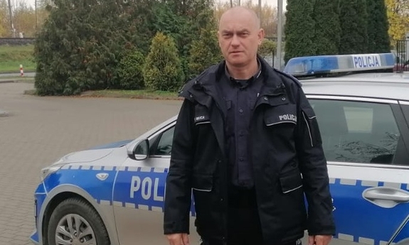 policjant stoi przy radiowozie policyjnym