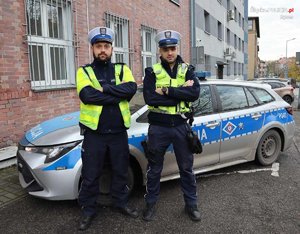 dwóch policjantów ruchu drogowego, którzy stoją przed radiowozem