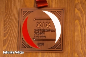 Brązowy medal z napisem XIX Mistrzostw Polski w ju-jitsu leży na brązowym stole