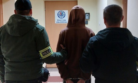Dwóch policjantów prowadzi zatrzymanego przez korytarz