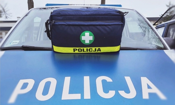 torba medyczna koloru granatowego ustawiona na masce oznakowanego radiowozu