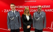 dwaj policjanci i kobieta wyróżnieni odznaką Honorowy Dawca Krwi – Zasłużony dla Zdrowia Narodu