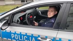Za kierownicą radiowozu siedzi umundurowany policjant