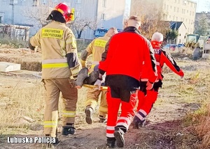 Strażacy i ratownicy medyczni niosą na noszach uratowanego mężczyznę