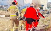 Strażacy i ratownicy medyczni niosą na noszach uratowanego mężczyznę
