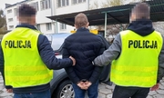 Policjanci z zatrzymanym mężczyzną zakutym w kajdanki