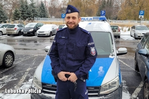 policjant stoi przed radiowozem