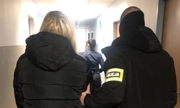 zatrzymana kobieta prowadzona korytarzem przez policjanta