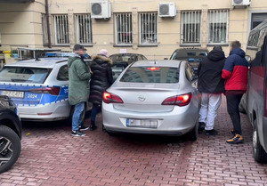 na parkingu przy nieoznakowanym radiowozie dwoje zatrzymanych z nieumundurowanymi funkcjonariuszami policji