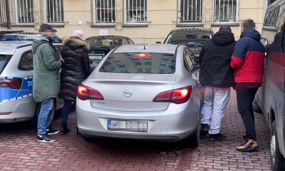 na parkingu przy nieoznakowanym radiowozie dwoje zatrzymanych z nieumundurowanymi funkcjonariuszami policji