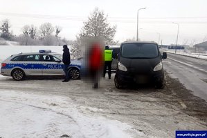 Zatrzymany czarny bus marki Ford. Obok oznakowany radiowóz