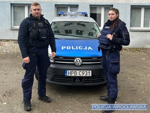policjant i policjantka przy radiowozie