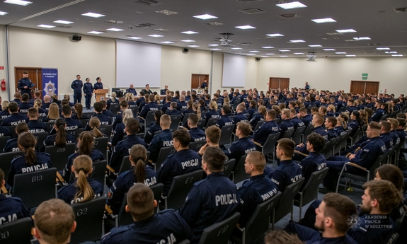 policjanci siedzą na auli na krzesłach ustawionych w rzędy