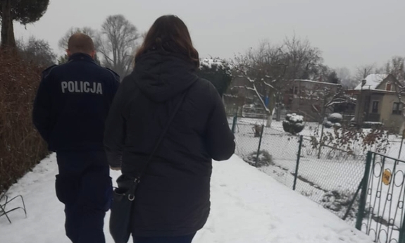 Policjant i kobieta idą zaśnieżoną dróżką po działkach ogrodowych