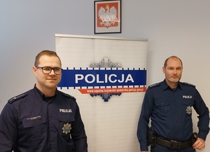 Policjanci stoją na tle napisu policja