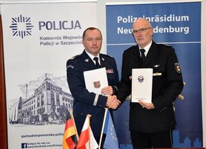 Policjanci stoją i podają sobie ręce