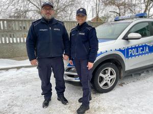 policjant i policjantka stoją przy radiowozie policyjnym