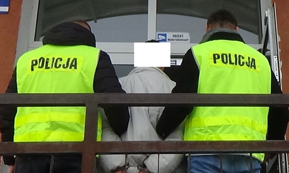 dwaj policjanci z zatrzymanym męzczyzną przed wejściem do Komisariatu III Policji w Radomiu