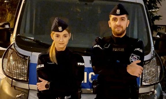 Noc. Dwoje policjantów stoi przed radiowozem