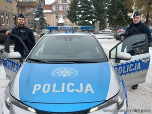 Umundurowani policjanci przy oznakowanym radiowozie