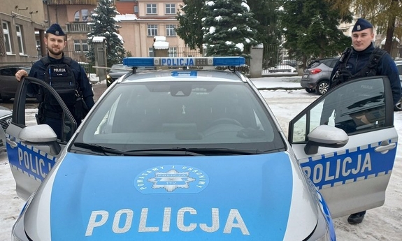 Umundurowani policjanci przy oznakowanym radiowozie