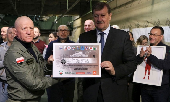 dwaj mężczyźni trzymają symboliczny czek, na którym wypisana jest kwota zebranych pieniędzy: 34150 złotych i 250 euro