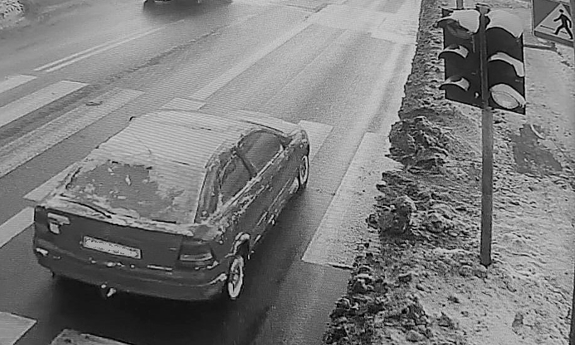 Zaśnieżony opel jedzie ulicą w tle inne pojazdy