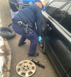 policjant w trakcie wymiany koła w samochodzie