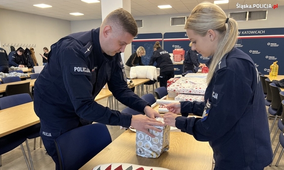policjant i policjantka pakują wspólnie prezent