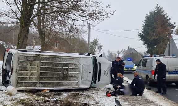 Dach wywróconego na bok busa, obok radiowóz i policjanci, którzy zatrzymali 15-latka
