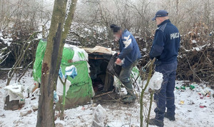 policjant i mężczyzna stoją przy prowizorycznym namiocie