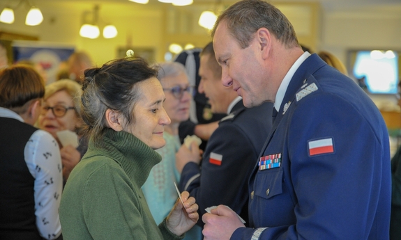 policjant dzieli się opłatkiem z kobietą