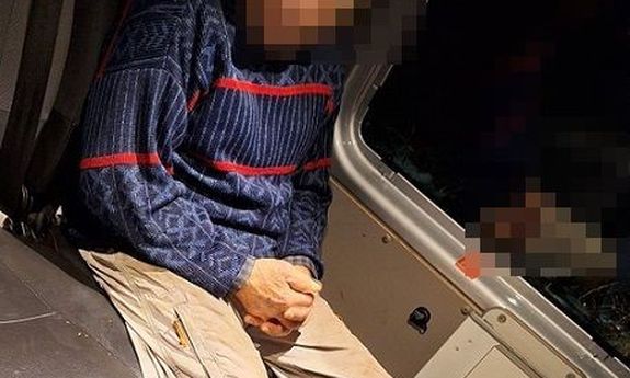 W radiowozie siedzi odnaleziony mężczyzna. Ma na sobie niebiesko-czerwony sweter