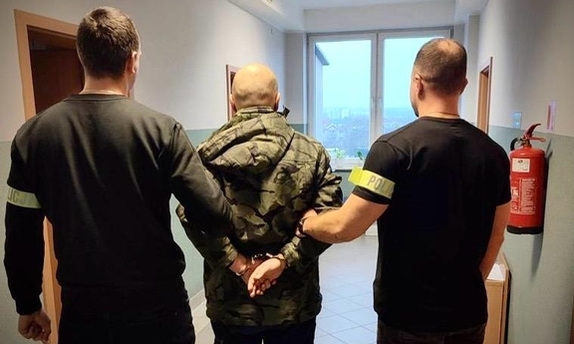 dwaj policjanci prowadza zatrzymanego
