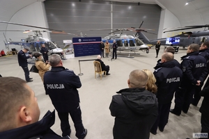 Policjanci i inni goście konferencji w hangarze, w tle śmigłowiec