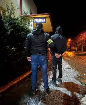 policjant prowadzi mężczyznę zakutego w kajdanki