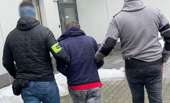 dwóch policjantów prowadzi zatrzymanego mężczyznę