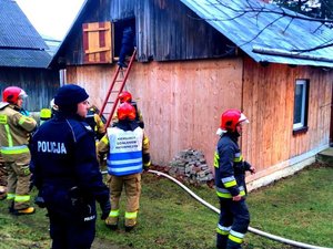 strażacy i policjant przy budynku, w którym wybuchł pożar