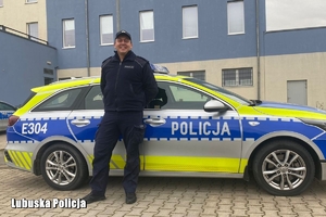 policjant stoi przy radiowozie policyjnym